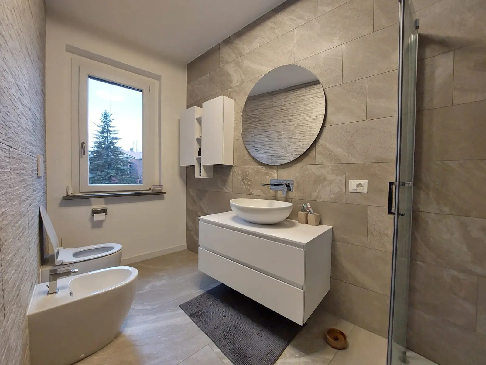 Bagno ristrutturato con vasca, rivestimento decorativo e arredo su misura