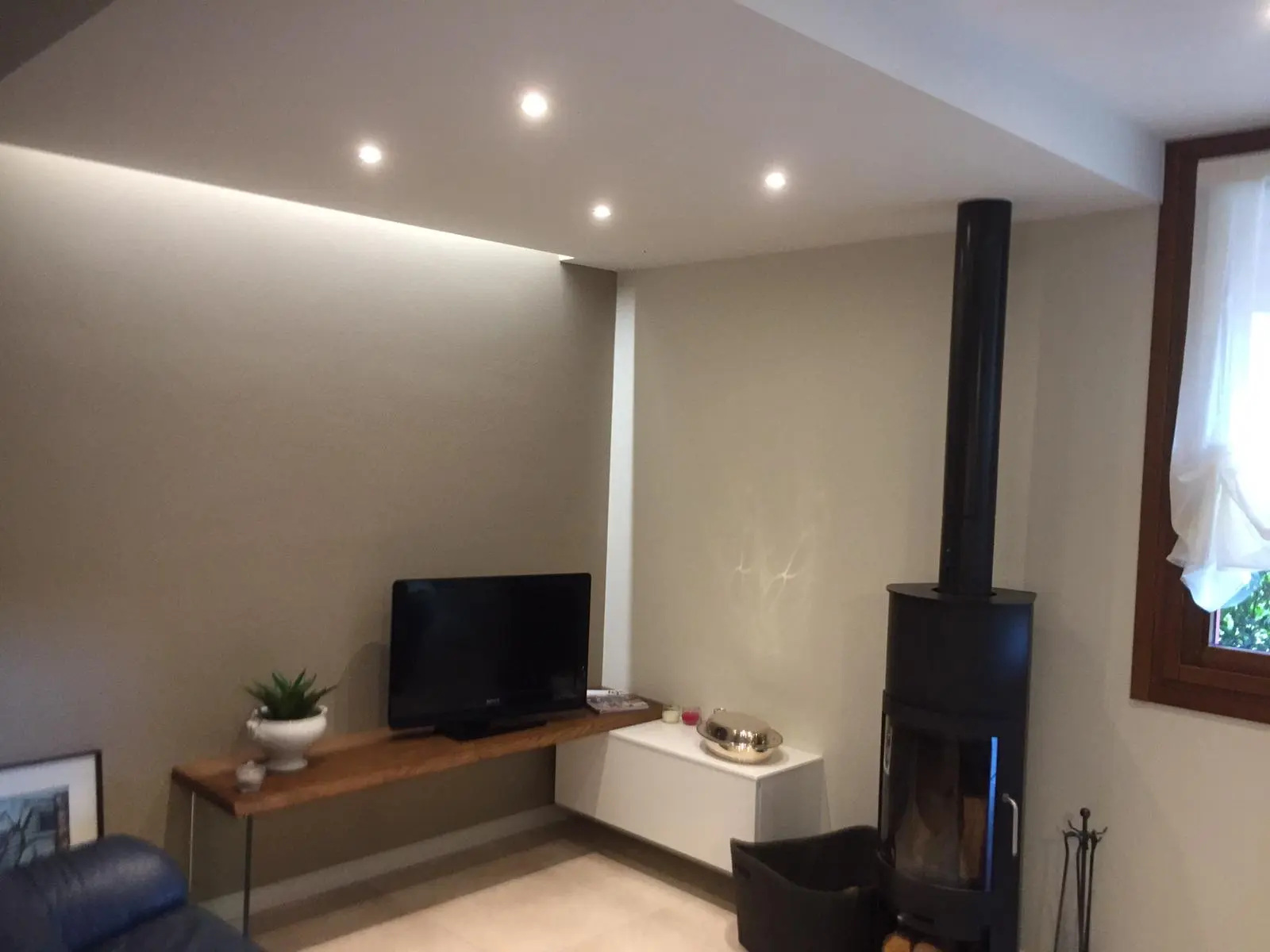 Soggiorno ultimato con pareti finite, illuminazione a soffitto e stufa